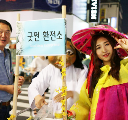굿쩐환전소라고 써있는 팻말을 든 한복을 입은 여성