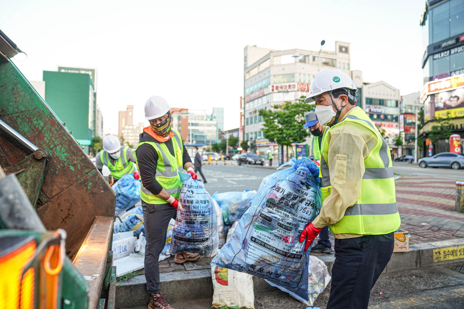 (07.01.빅마트일원) 쓰레기가 담긴 봉투들을 쓰레기차에 옮기는 목포시장과 환경미화원 분들의 모습