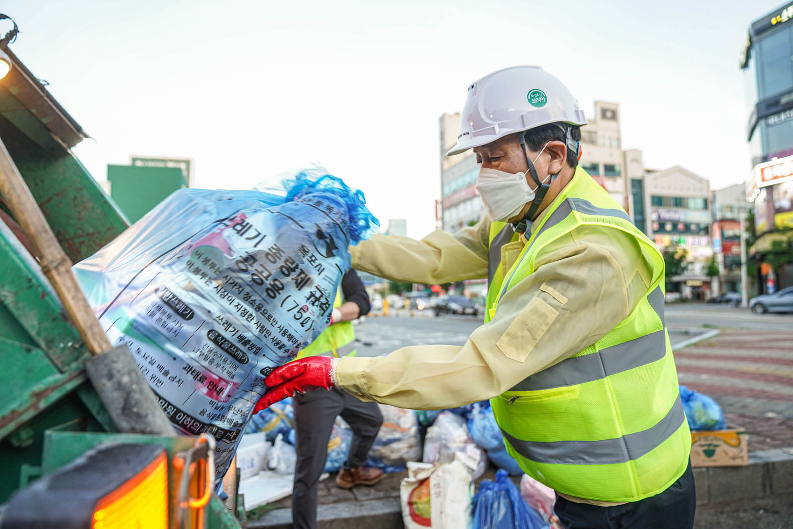 (07.01.빅마트일원) 쓰레기가 담긴 봉투를 쓰레기차에 옮기는 목포시장의 모습 