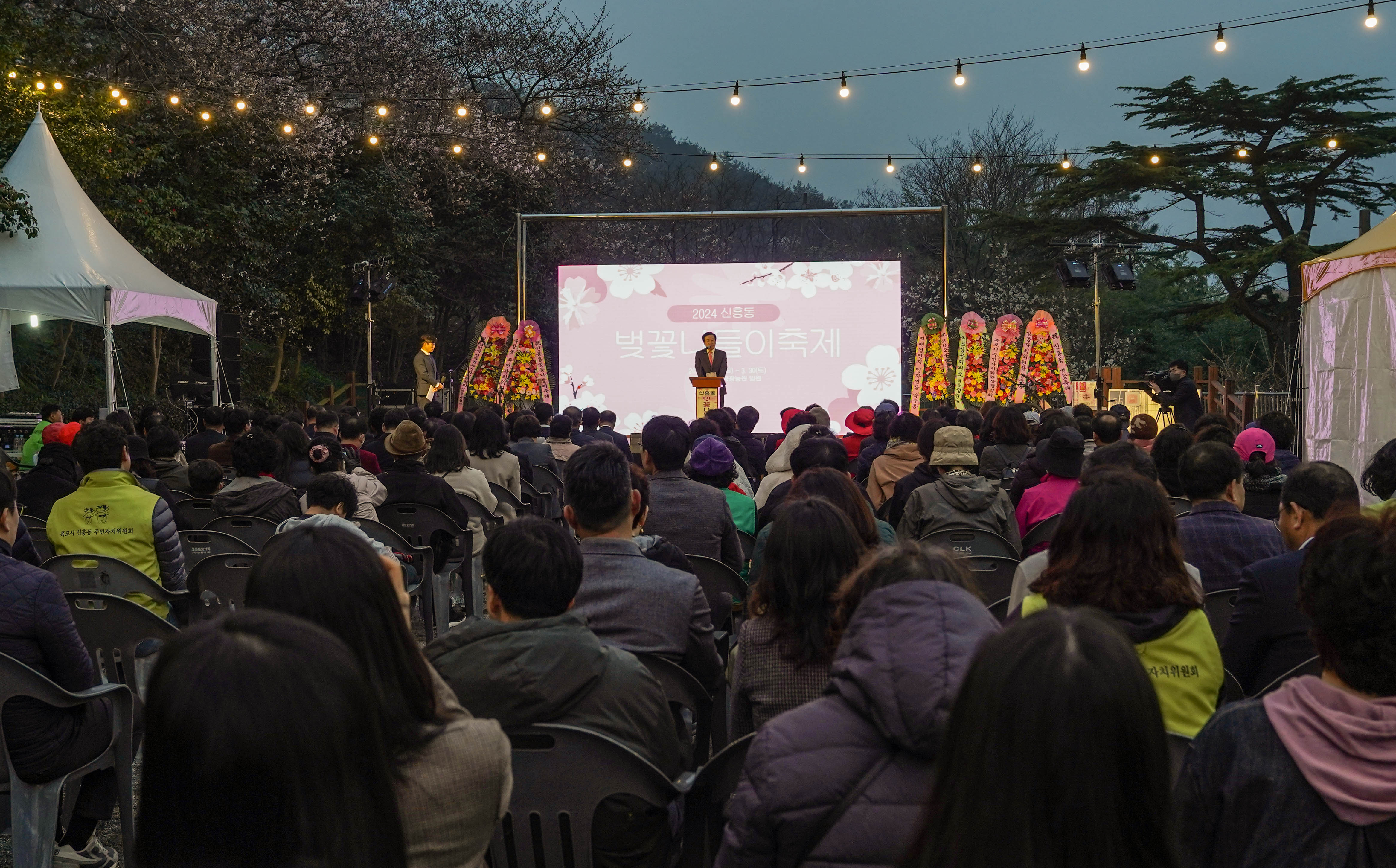 2024년 신흥동 벚꽃나들이 축제 행사에서 목포 시장이 단상에 올라서 연설을 하고, 시민들이 앉아서 경청하고 있는 모습