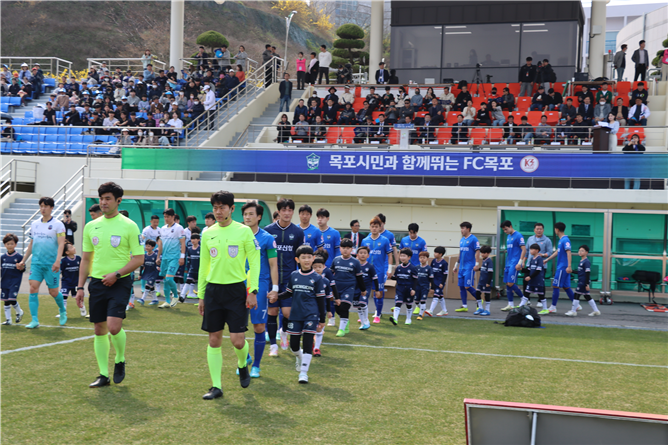 FC 목포 축구단 선수들이 아이들과 함께 경기장에 입장하고 있는 모습