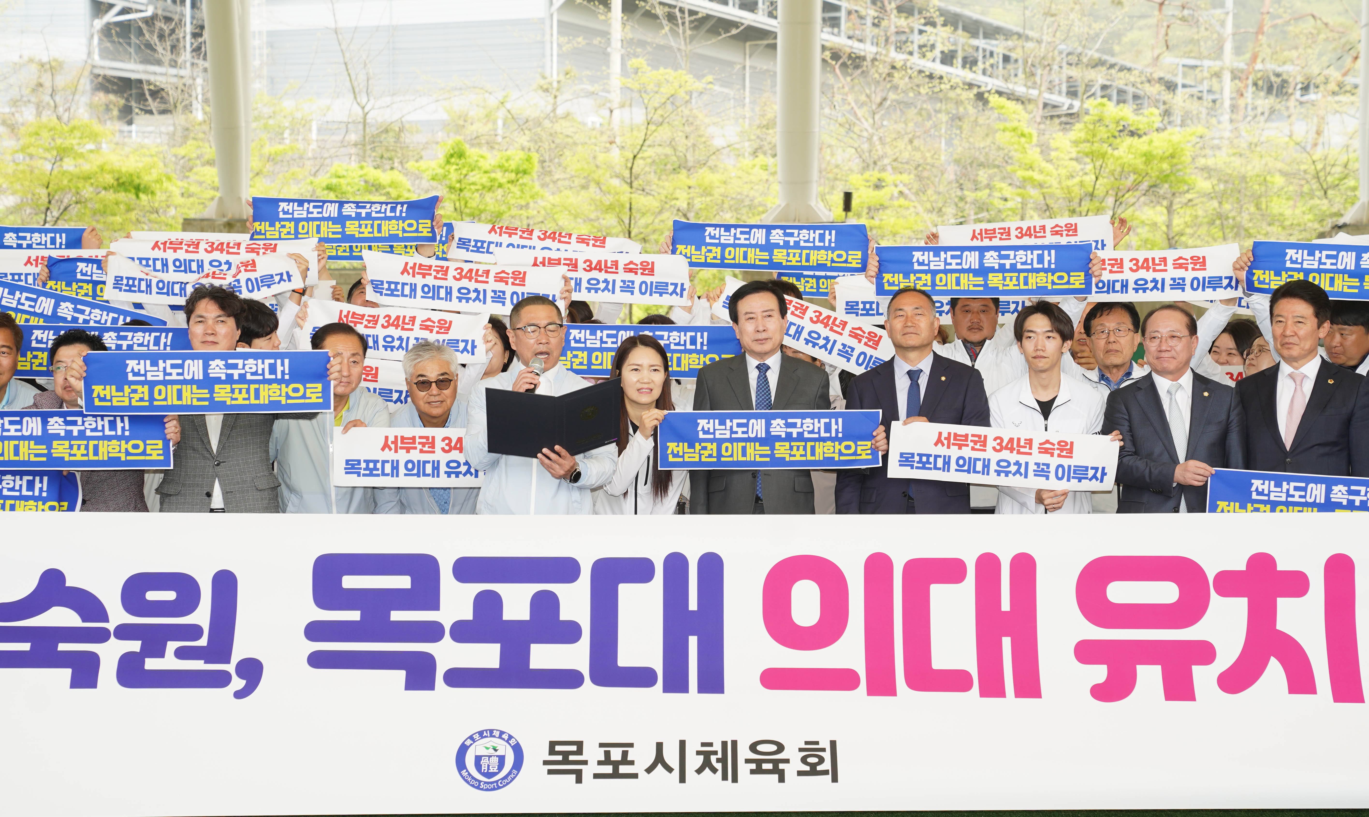 김성대 체육 회장이 마이크를 들고 국립 목포대 의과대학 유치을 위한 성명서를 발표하는 모습