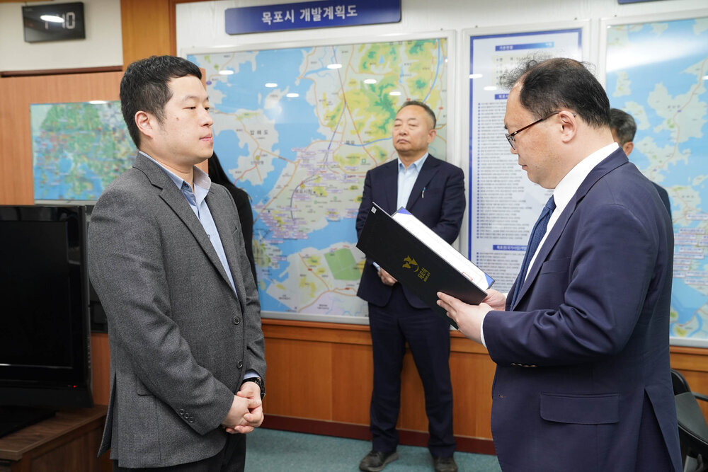 수시인사 임용장 수여식에서 정장을 입은 남성이 회색 정장을 입은 남성 직원에게 임용장을 전달하는 모습