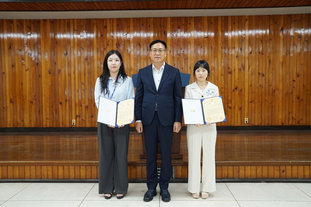 패 수여식에서 정장과 단정한 복장의 수상자들이 상장을 들고 관계자와 함께 단체 기념 촬영을 하고 있는 모습이다.
