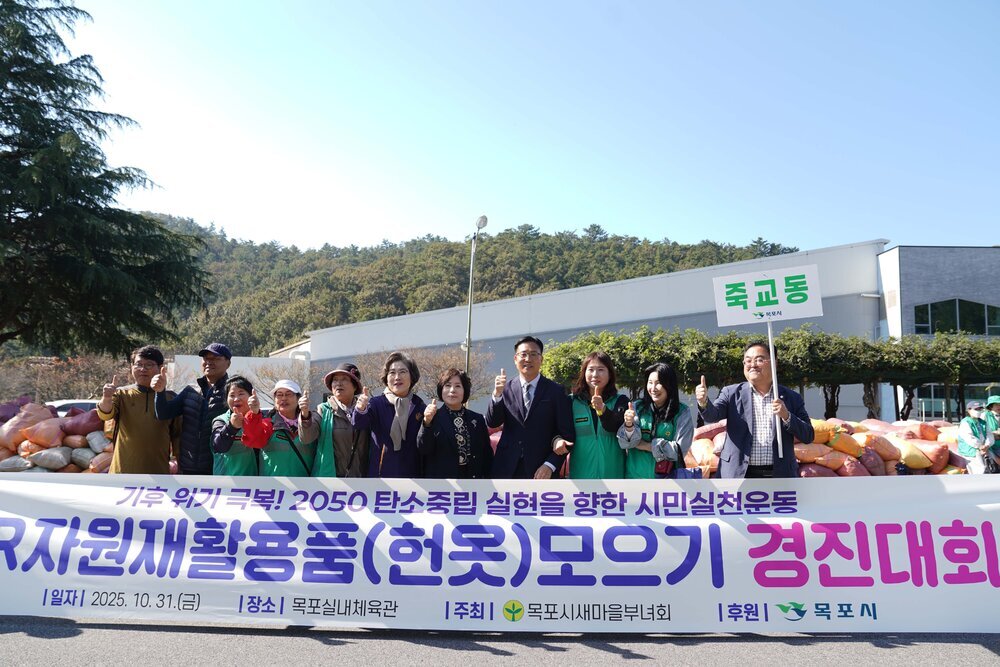 '3R 자원재활용품(헌옷) 모으기 경진대회' 현수막 뒤에서 죽교동 피켓을 든 참가자들이 엄지척 포즈를 취하고 있다. 배경에는 목포실내체육관 인근 전경과 헌옷 자루들이 보인다.