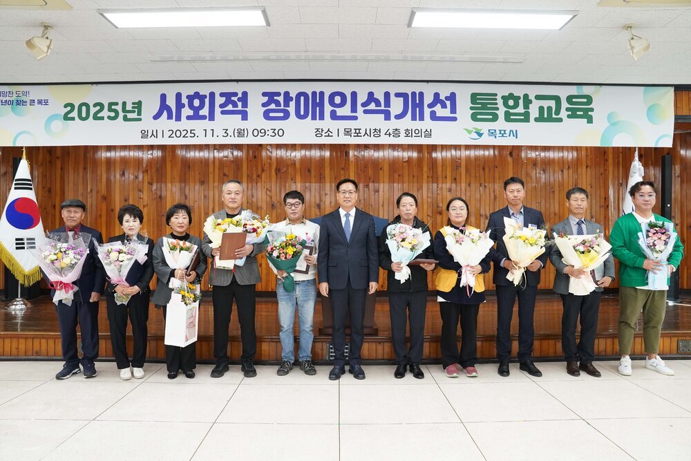 시상식 단체 기념사진. '2025년 사회적 장애인식개선 통합교육 | 일시 2025. 11. 3.(월) 09:30 | 장소 목포시청 4층 회의실 | 목포시' 현수막 아래에서 시상자와 수상자 10명이 꽃다발과 상패를 들고 나란히 서 있음.