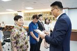 정장 차림의 관계자가 꽃무늬 상의를 입은 여성 수상자에게 표창패를 전달하며 읽고 있는 모습이다.
