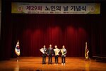 노인의 날 기념식에서 관계자와 수상자들이 꽃다발을 들고 단체 기념 촬영을 하고 있는 모습이다.