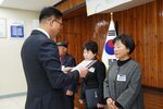 11월 정례조회로 정장을 입고 안경을 쓴 남성이 짧은 머리에 회색 상의를 입고 두 손을 가지런이 모은 자세로 곽옥희 수상자에게 상패를 수여 하고 있다.