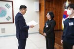 4월 정례조회에 정장을 입고 안경을 낀 남성이 검은정장을 입은 박신영에게 패를 수여하고 있다
